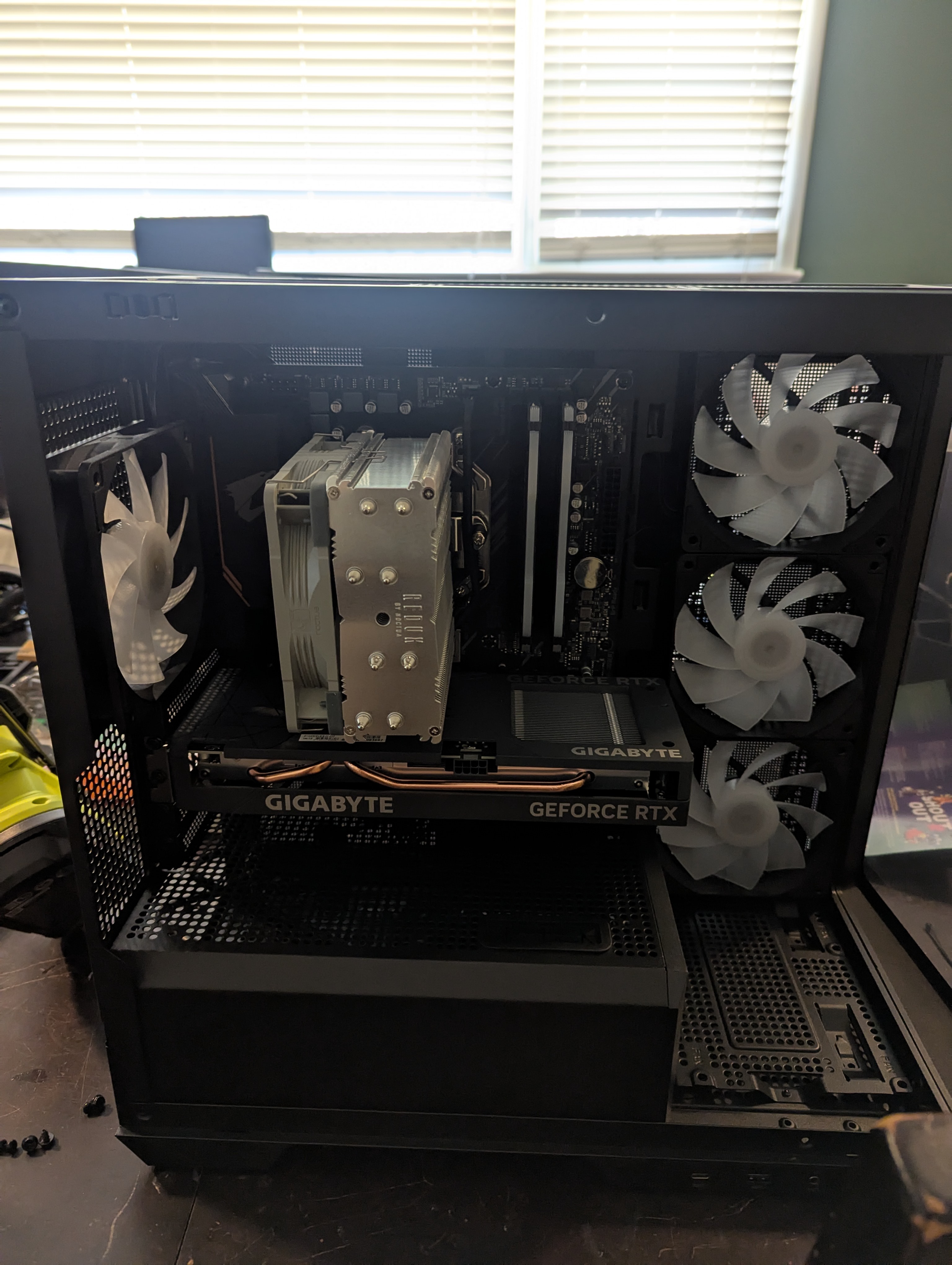 Open computer case showing motherboard, CPU cooler, and dual graphics cards during a build